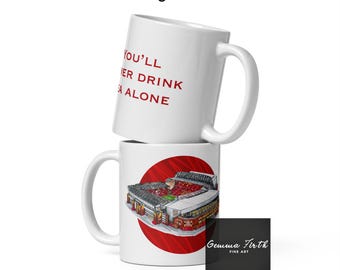 May include: Two white ceramic mugs stacked on top of each other. The top mug has the text "You'll Never Drink Alone" in red. The bottom mug features a stadium illustration inside a red circle. A black card with "Gemma Firth FINE ART" is on the right.