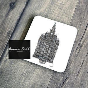 Puede incluir: Un posavasos cuadrado con una ilustración detallada en escala de grises de un edificio con una torre del reloj. El posavasos tiene esquinas redondeadas y el texto "Gemma Firth FINE ART" es visible en un cuadrado negro.
