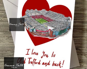 May include: A white greeting card featuring a detailed illustration of Old Trafford stadium within a red heart. The card includes the text "I love you to Old Trafford and back!" in red script. The card is placed on a neutral background.