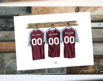 May include: Three maroon football jerseys with white numbers hanging on a wooden rack. The jerseys have grey sleeves and the text "ANY NAME" above the numbers.
