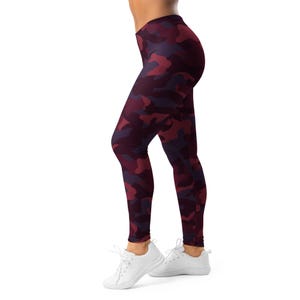 May include: Full-length leggings with a camouflage pattern in shades of burgundy, red, and purple. The leggings are worn with white athletic shoes. The fabric appears to be stretchy and form-fitting.