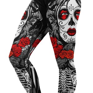 Peut inclure: Legging noir avec un motif de tête de mort mexicaine, des roses rouges et un motif de squelette. Le legging a une ceinture noire et est porté avec des baskets noires.