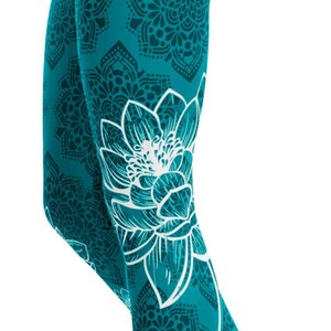 May include: Teal leggings with a white floral design on the lower leg and a repeating mandala pattern. The leggings are form-fitting and made of a stretchy material.