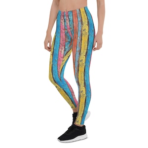 Op de afbeelding: Leggings met een kleurrijk, verweerd houten plankontwerp. De leggings hebben verticale strepen in tinten blauw, geel, roze en oranje. De leggings worden gedragen met zwarte sneakers.
