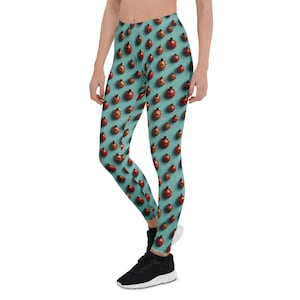 May include: Teal leggings with a repeating pattern of red and black ladybugs. The leggings are form-fitting and made of a stretchy material, suitable for athletic activities or casual wear.