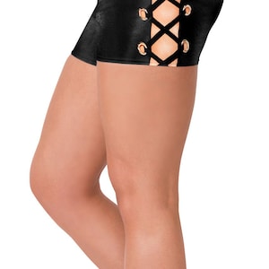 May include: Black athletic shorts with a lace-up design on the side. The shorts have gold-colored grommets and a shiny finish. The model is wearing white sneakers and a white top.