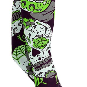 Peut inclure: Leggings avec un motif répétitif de crânes en sucre dans des tons vert citron vif, noir et blanc. Le design comprend des détails floraux complexes, des motifs de toiles d'araignée et des visages de crânes stylisés avec des orbites décorées.
