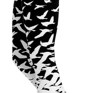 Könnte beinhalten: Schwarze und weiße Leggings mit einem Muster aus fliegenden Vögeln. Die weißen Vögel heben sich vom schwarzen Hintergrund ab. Die Leggings sind knielang.
