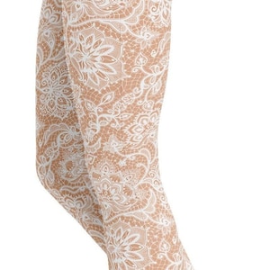 Peut inclure: Legging beige avec un motif de dentelle blanche. Le legging présente un motif floral détaillé, créant un look délicat et féminin. Le tissu semble extensible et moulant. La longueur est d'environ 90 cm.