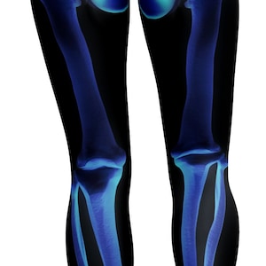 May include: Black leggings with a blue and white skeletal design. The leggings feature a detailed illustration of the human leg bones, including the pelvis, femur, tibia, and fibula. The design is a medical or anatomical theme.