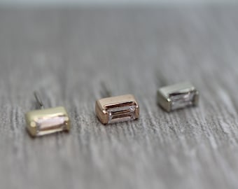 May include: Three body jewellery pieces in different colours, each featuring a rectangular clear gem. The jewellery is made of gold, rose gold and silver.