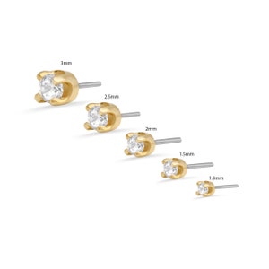 May include: Five gold-toned stud earrings with clear cubic zirconia stones. The earrings are shown in order of size, from largest to smallest, with the measurements 3mm, 2.5mm, 2mm, 1.5mm, and 1.3mm.