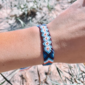 May include: A colorful friendship bracelet with a chevron pattern in blue, white, orange, and brown.