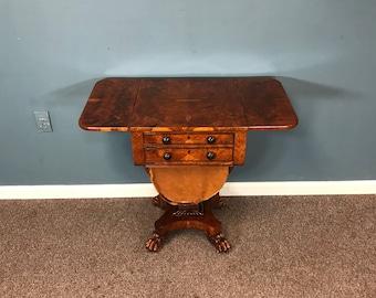 May include: A brown wooden drop-leaf table with two drawers and a curved base. The table is on a brown carpet.