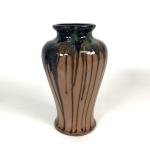 Pode incluir: Um vaso de cerâmica marrom com esmalte preto e azul pingando pelas laterais. O vaso tem um corpo arredondado e um pescoço estreito.