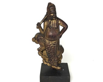Może przedstawiać: Drewniana statuetka w kolorze złotym i brązowym przedstawiająca bóstwo siedzące na chmurze z mieczem w ręku. Statuetka stoi na czarnej drewnianej podstawie.