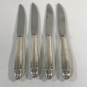May include: Four silver dinner knives with ornate handles.