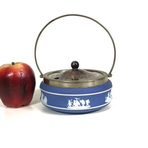 May include: Blue and white ceramic sugar bowl with a silver lid and a brass handle. The bowl has a white floral design.