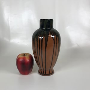 Pode incluir: Um vaso de cerâmica marrom com esmalte preto e verde pingando pelas laterais. O vaso tem um corpo arredondado e uma borda alargada.