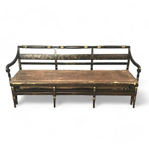 May include: A black and gold painted wooden sofa with a brown fabric cushion. The sofa has a curved back and arms, and is decorated with floral motifs.