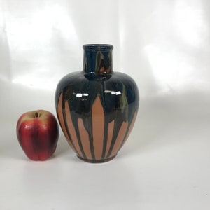 Pode incluir: Um vaso de cerâmica marrom com um esmalte azul e verde. O vaso tem uma base larga e um pescoço estreito.