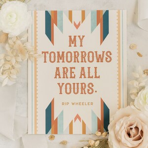 May include: A rectangular print with the text "MY TOMORROWS ARE ALL YOURS." in a vintage font. The design includes geometric shapes in teal, orange, and blue. The author's name, "RIP WHEELER," is below the quote. The print is surrounded by white flowers and ribbons.