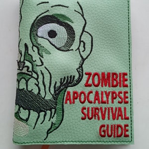 May include: A green leather notebook with a zombie face embroidered on the front. The text "Zombie Apocalypse Survival Guide" is embroidered in red on the front.
