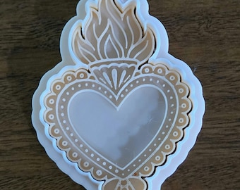 Op de afbeelding: Een witte plastic koekjesvorm in de vorm van een heilig hart met een vlam aan de bovenkant. Het ontwerp bevat ingewikkelde reliëfdetails, waaronder een geschulpte rand en decoratieve lijnen. De tekst Style 6 is linksboven zichtbaar.