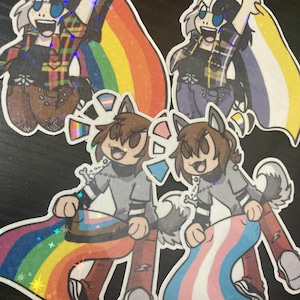 May include: Four cartoon characters holding different pride flags. The characters are a wolf, a bunny, and two wolf-like creatures. The flags are rainbow, transgender, and a yellow, purple, and white flag.