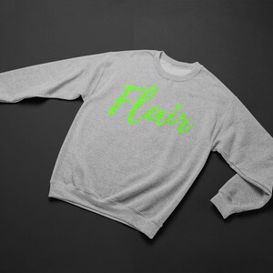 K&ouml;nnte beinhalten: Ein grauer Pullover mit dem Wort "Flair" in Gr&uuml;n auf der Vorderseite.