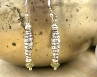 May include: Silver earrings with a textured, woven design and a light green gemstone at the bottom.