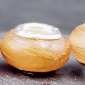 May include: Three small, round, light brown objects with a silver-colored top. The objects have a textured, fibrous appearance. The silver tops are smooth and reflective. The objects are arranged in a row, slightly angled.