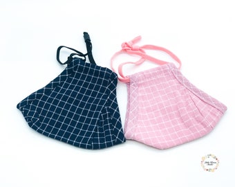 May include: Two fabric face masks with checkered patterns. One mask is navy blue with white checks and the other is pink with white checks.