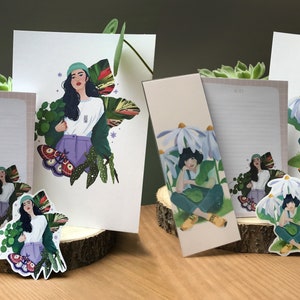 Peut inclure: Un ensemble de quatre cartes et autocollants illustrés représentant une femme aux longs cheveux noirs portant un chapeau vert et une chemise blanche. La femme est entourée de plantes et de fleurs vertes. Les cartes et les autocollants sont imprimés sur du papier cartonné blanc et ont une finition mate.