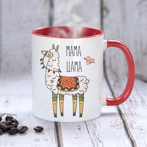 Puede incluir: Taza de cer&aacute;mica blanca con borde y asa rojos. La taza presenta una llama de dibujos animados con una silla de montar y el texto "Mama Llama" con un coraz&oacute;n y una flecha.