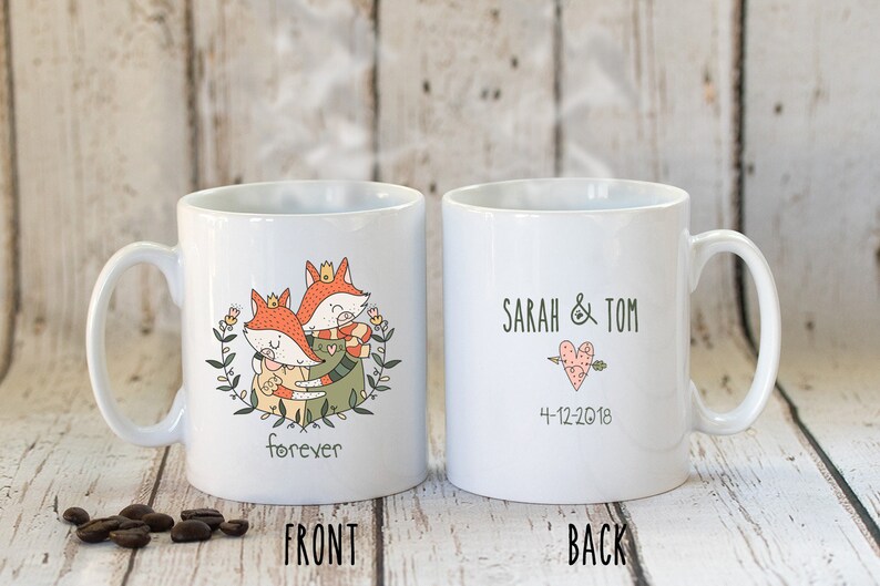 Puede incluir: Taza de cer&aacute;mica blanca con un dise&ntilde;o de dos zorros abraz&aacute;ndose y la palabra "forever" en la parte delantera. La parte posterior de la taza tiene el texto "SARAH & TOM" con un coraz&oacute;n y una flecha y la fecha "4-12-2018".