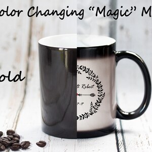 Puede incluir: Taza m&aacute;gica que cambia de color con un dise&ntilde;o en blanco y negro. La taza es negra cuando est&aacute; fr&iacute;a y revela un dise&ntilde;o blanco con una corona, una flecha y el texto "& Robert 7-17" cuando est&aacute; caliente.