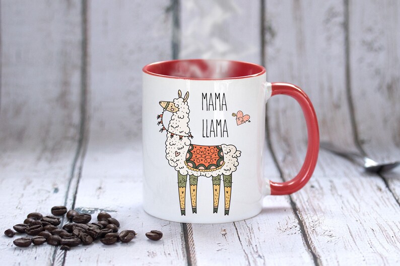 Puede incluir: Taza de cer&aacute;mica blanca con borde y asa rojos. La taza presenta una llama de dibujos animados con una silla de montar y el texto "Mama Llama" con un coraz&oacute;n y una flecha.