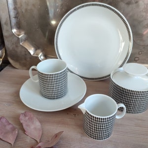 May include: A white ceramic tea set with a black geometric pattern. The set includes a teapot, creamer, sugar bowl, and two cups and saucers.