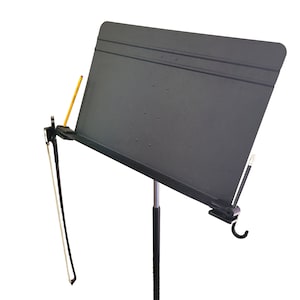 Könnte beinhalten: Ein schwarzer Notenständer mit einem Metallständer und einem schwarzen Notenhalter. Der Ständer hat einen Clip zum Halten eines Stifts oder Bleistifts und einen Haken zum Aufhängen eines Bogens.