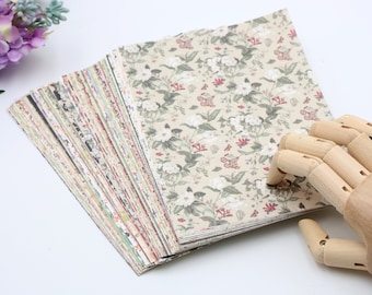 May include: A stack of patterned paper sheets with a floral design in shades of beige, green, and red. The paper is arranged in a fan shape, with the top sheet showing a close-up of the floral pattern.