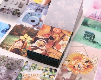 May include: A stack of colorful patterned paper cards with images of flowers, cameras, and a girl wearing a sweater. The cards are perfect for scrapbooking, journaling, or crafting.
