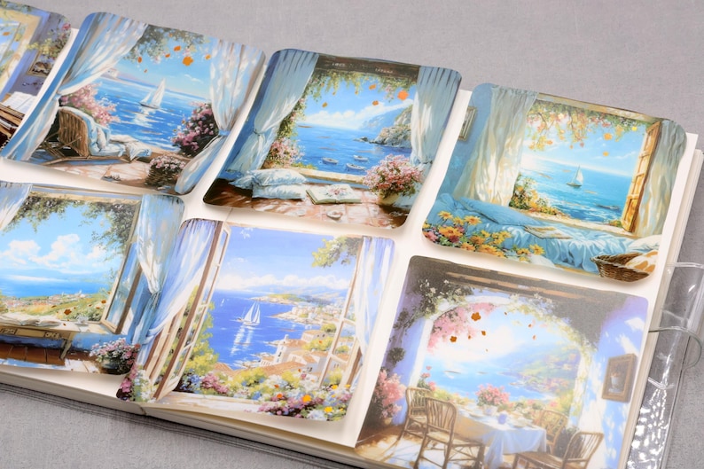 May include: A collection of stickers featuring scenic views of the ocean and coastal landscapes. Each sticker showcases a different window view with blue skies, sailboats, and colorful flowers. The stickers are arranged in a notebook.