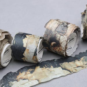 May include: Three rolls of decorative paper tape featuring a vintage aesthetic with patterns of aged parchment, black lace, and printed text. The white inner cores are printed with the text "have a good day." and additional small characters.