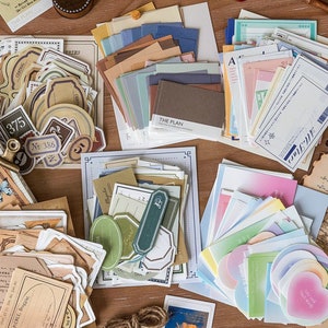 May include: Assortment of vintage-style paper stickers and decorative papers in various colors and designs. The stickers feature a variety of shapes, including circles, squares, and rectangles. The papers include a variety of patterns, including stripes, polka dots, and floral designs. The stickers and papers are perfect for scrapbooking, journaling, and other craft projects.