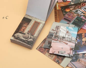 May include: A stack of vintage-style photo cards with images of a scooter, a city street, and a building. The cards are arranged in a fan shape and have a worn, faded look.