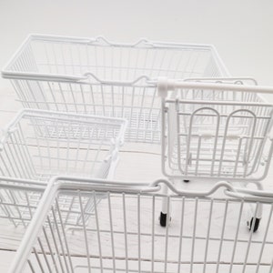 May include: Four white wire shopping baskets, three are rectangular and one is a smaller, wheeled cart.