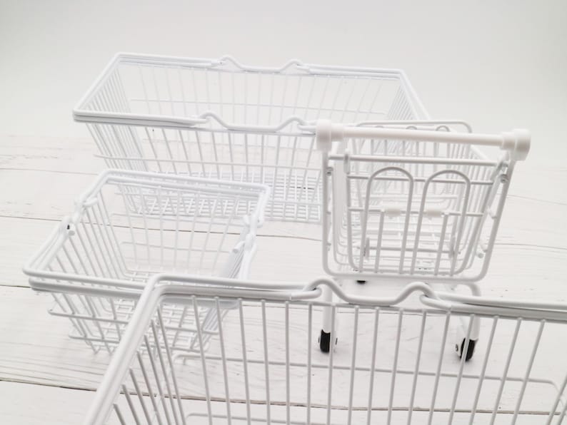 May include: Four white wire shopping baskets, three are rectangular and one is a smaller, wheeled cart.