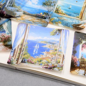 May include: Several decorative square art prints featuring coastal scenes with sailboats, open windows, and floral arrangements. The prints showcase a vibrant color palette of blues, whites, and greens, evoking a sense of tranquility and scenic beauty.