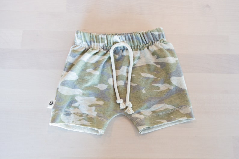 May include: Camouflage print shorts with a white drawstring. The shorts have a relaxed fit and are made of a soft, comfortable fabric.